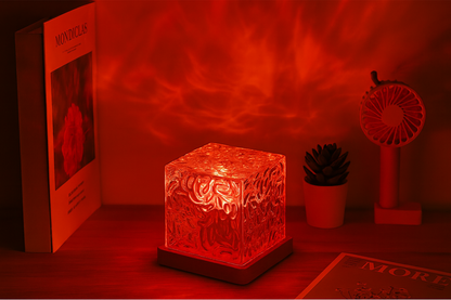 Glass cube night light projecting red ambient lighting in a cozy bedroom scene.