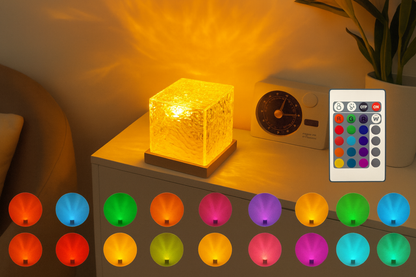 Glass cube LED projector displaying warm yellow light with remote control and color options.