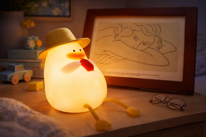 Color-changing silicone duck night light glowing warm yellow on a wooden nightstand