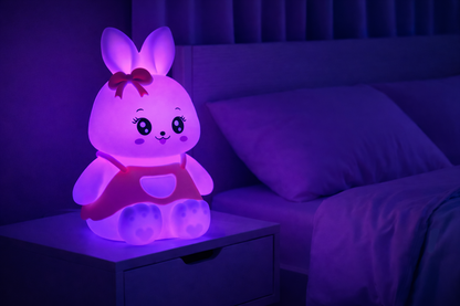 Color-changing silicone bunny night light glowing purple on a bedside table