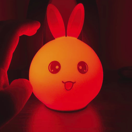 Color-changing silicone bunny night light glowing in a dark room
